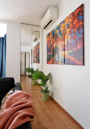 Ein modernes Wohnzimmer mit einer Couch, einem großen Spiegel und einer Zimmerpflanze.