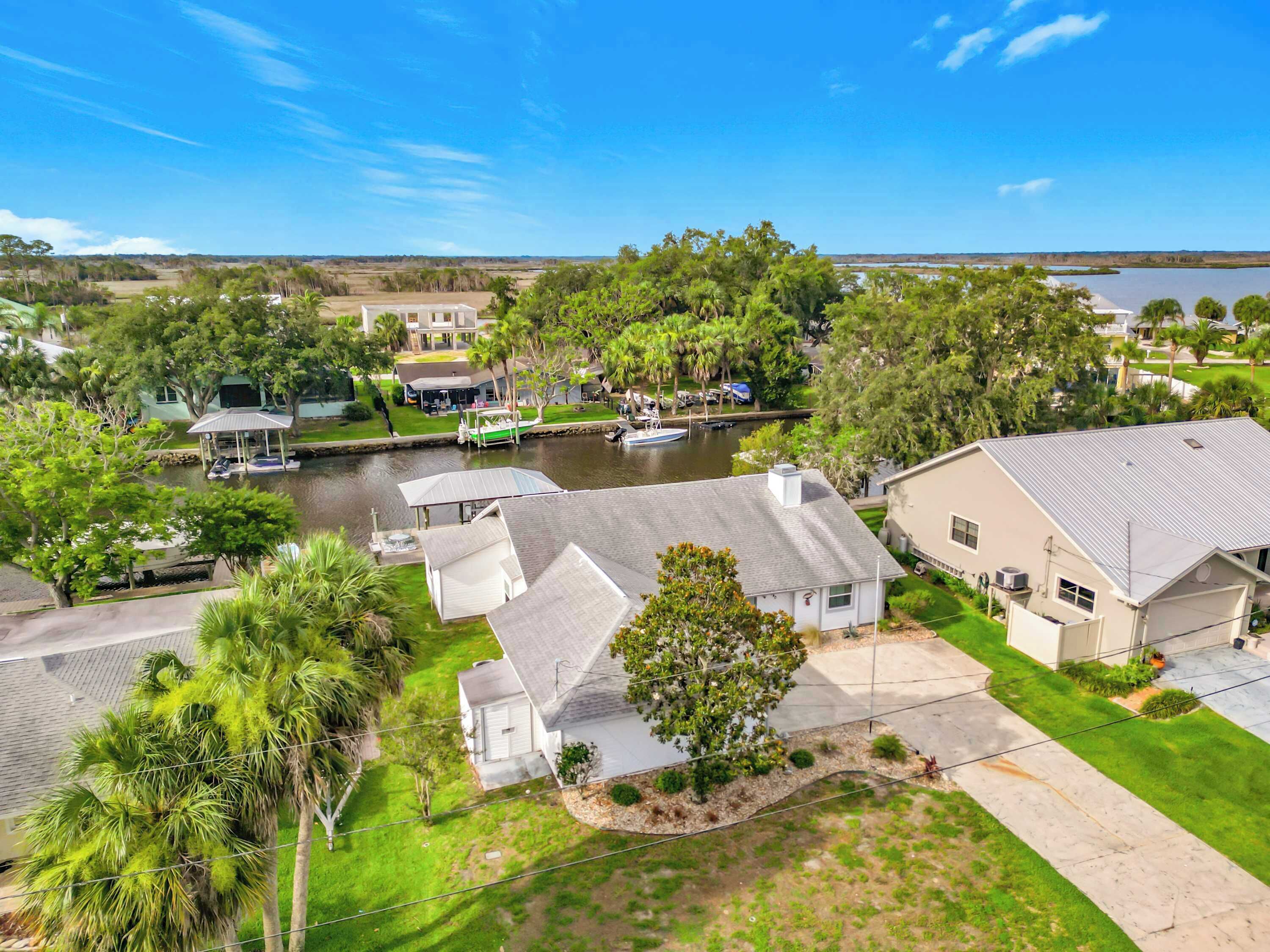 A residential area with houses, a canal, and a body of water in the background.