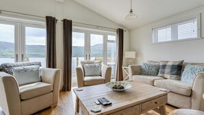 Un salon spacieux avec une table basse en bois, deux canapés et une vue sur l’extérieur.