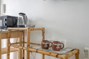 A bamboo chair with a woven backrest and a table with a patterned tablecloth. Two brown mugs with 'Felicidad Café' text are on the table. - Central Polynesia Apartment in Ronda (Ronda)