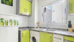 Cuina compacta amb rentadora, un rentabiosquets i una finestra amb vista.