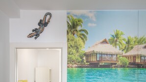 A room with a door, a wall-mounted decorative piece, and a large window with a view of overwater bungalows and palm trees. - Central Polynesia Apartment in Ronda (Ronda)