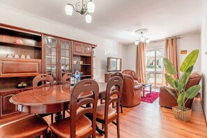 Ein Essbereich mit Holztisch und -stühlen, einem Schrank mit Glastüren und einer großen Pflanze.