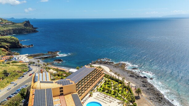 Um hotel à beira-mar com piscina, painéis solares e vista para o oceano.