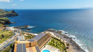 Ett hotell vid kusten med pool, solpaneler och utsikt över havet.