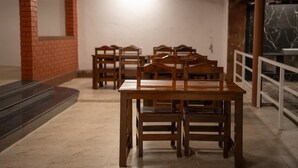 Una habitación con pared de ladrillo, una mesa de madera con sillas y suelo de mármol.