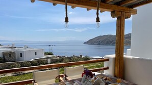 A wooden table set with breakfast, overlooking a coastal view with buildings and the sea. - Cosy Villa Walking Distance to a Mykonian Beach (Mykonos)