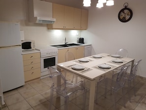 Uma cozinha compacta com fogão, micro-ondas, pia e uma mesa de jantar posta para quatro pessoas.