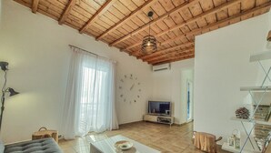 A living room with a wooden ceiling, a sofa, a coffee table, a TV, and a staircase with a railing. - Cosy Villa Walking Distance to a Mykonian Beach (Mykonos)