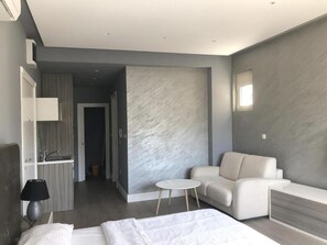 Ein modernes Hotelzimmer mit einem Bett, einem kleinen runden Tisch, einer Couch und einer eingebauten Bank.