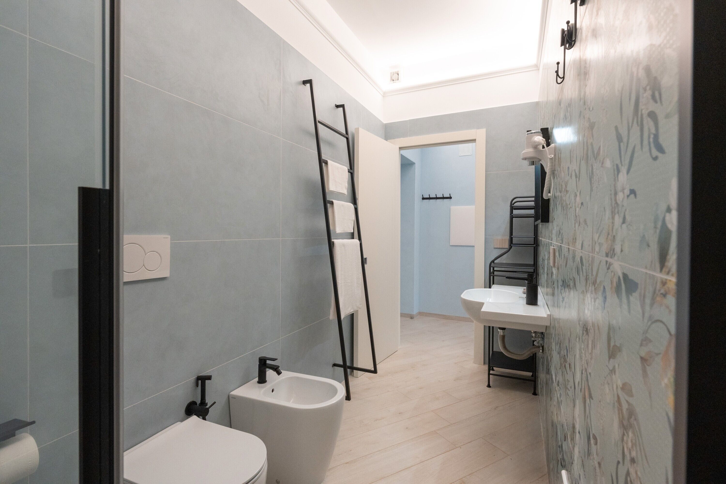 Ein Badezimmer mit Bidet, Toilette und Waschbecken, einem Handtuchhalter und einer Duschkabine.
