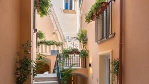 A narrow corridor with a staircase, potted plants, and a door at the end. - Apartment 'Parmenide Family' with Wi-Fi and Air Conditioning (Ascea)