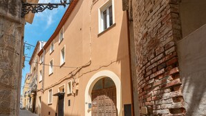 A narrow street with a building featuring a large wooden door, stone walls, and a clear blue sky. - Apartment 'Parmenide Family' with Wi-Fi and Air Conditioning (Ascea)