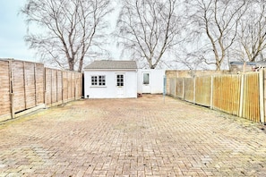 A brick courtyard with a white building, wooden fences, and leafless trees.