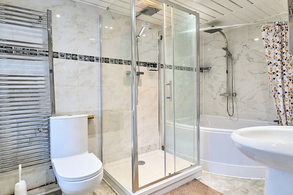 A modern bathroom with a glass-enclosed shower, a white toilet, and a bathtub.