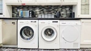A kitchen with white cabinets, a tiled backsplash, and two Bosch washing machines. - House Sleeps 8 - Free Parking & Wifi (Birmingham)