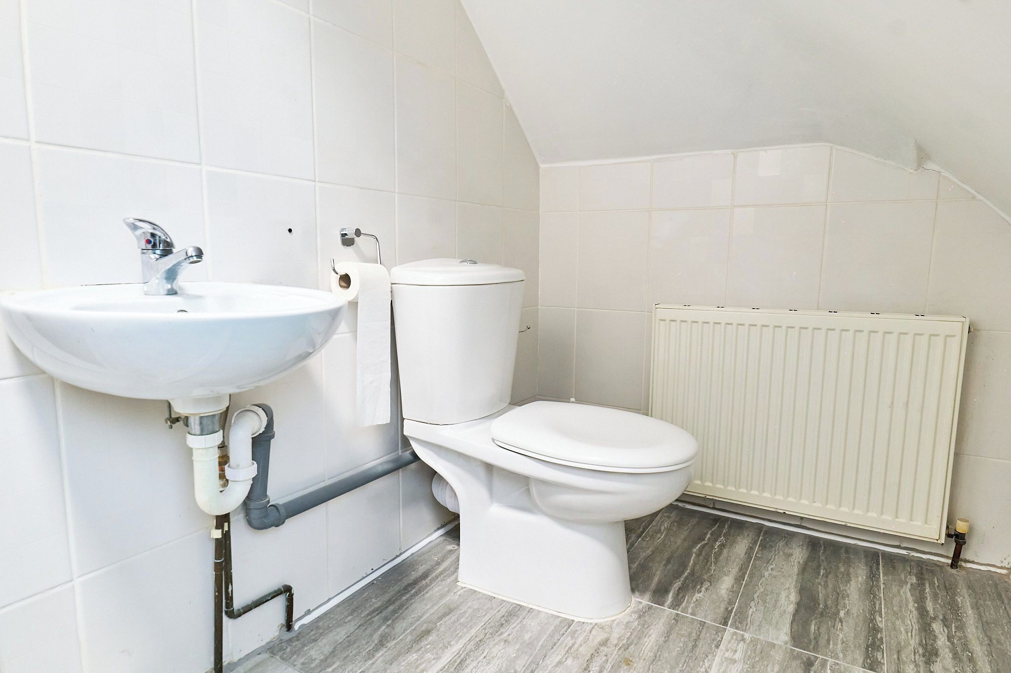 A bathroom with a white sink, toilet, and radiator.