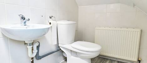 A bathroom with a white sink, toilet, and radiator.