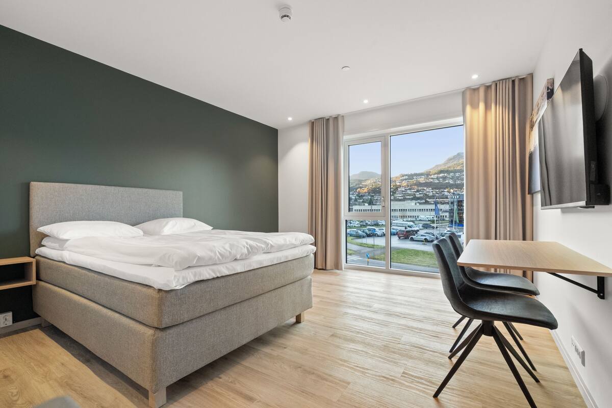 A hotel room with a bed, a desk, and a chair.