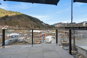 A construction site with a view of a forested hill and a building under construction.