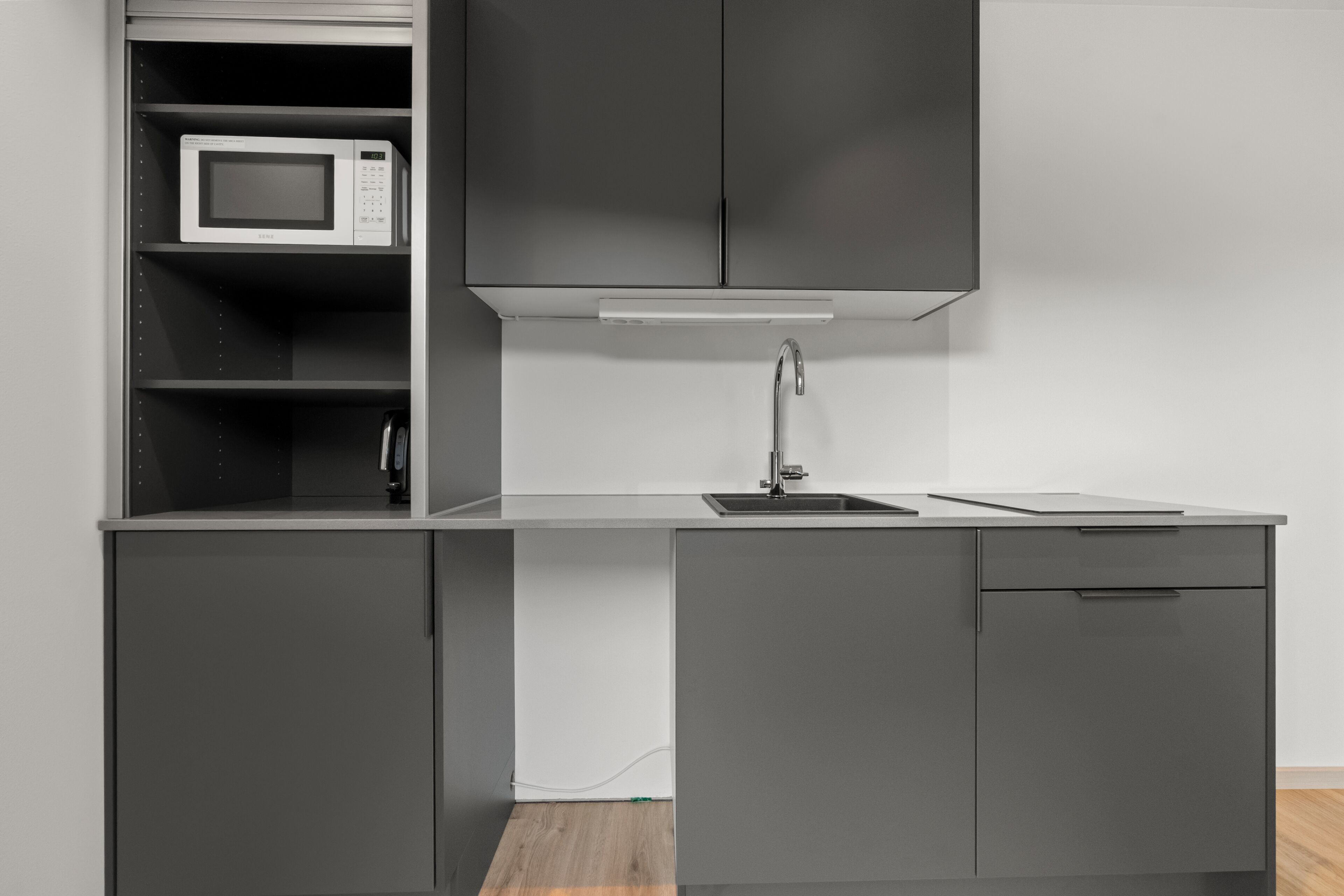 A modern kitchen with a microwave, a sink, and cabinets.