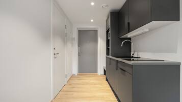 Una cocina moderna con armarios oscuros, piso de madera y una puerta blanca.