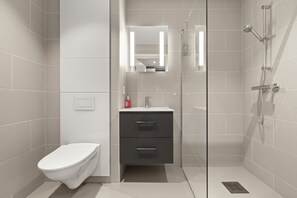 A modern bathroom with a toilet, a vanity with drawers, a glass shower enclosure, and a mirror. - Skudeløken Apartment Hotel (Vestland)