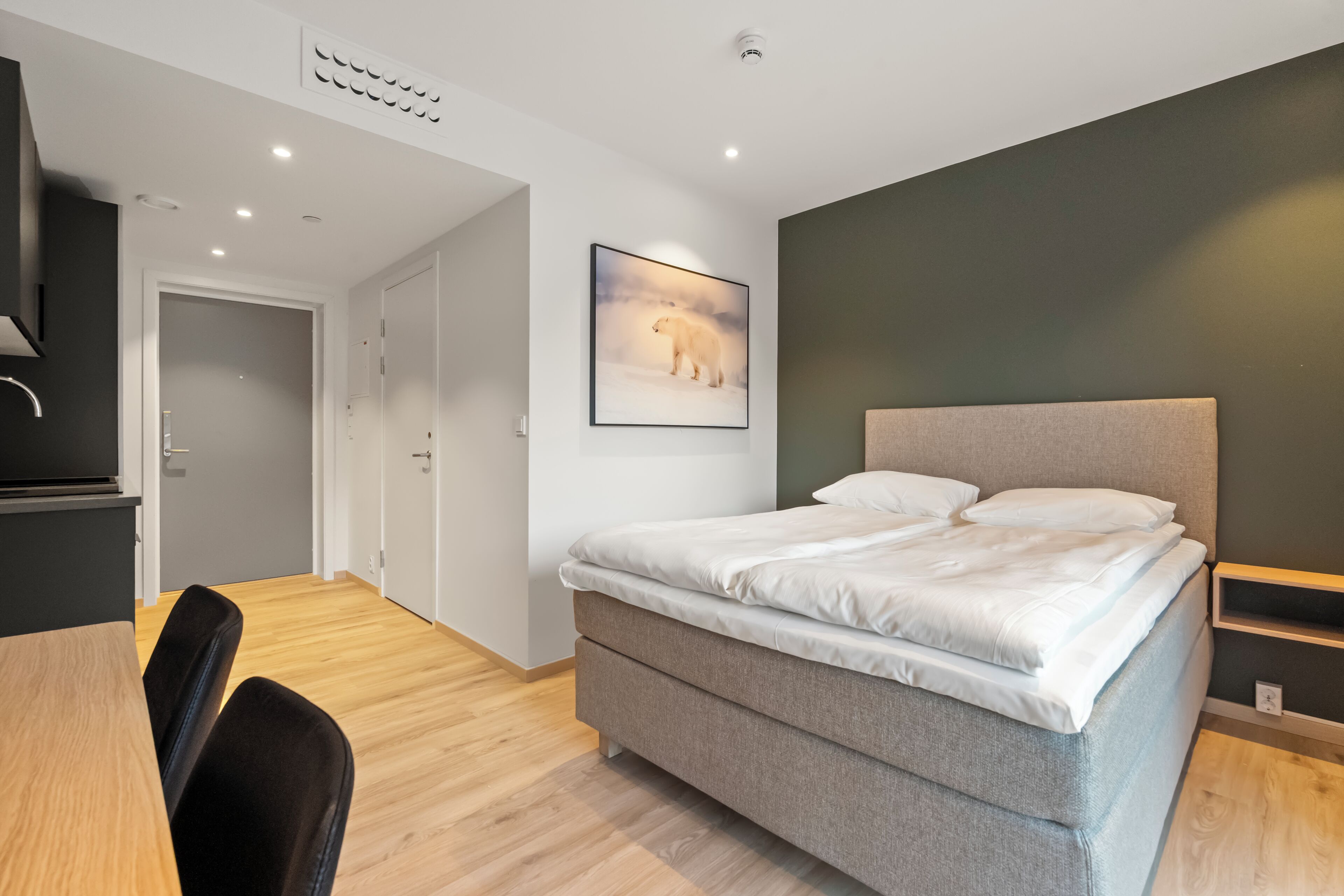 Un dormitorio moderno con cama, escritorio y silla.