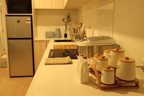 A kitchen with a refrigerator, coffee maker, and jars on the counter. - Stylish Central Christchurch Apartment | Prime Location & Comfort (Christchurch)