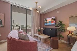Ein modernes Wohnzimmer mit einer Couch, einem Fernseher, einer Bank, einem Tisch und Topfpflanzen.