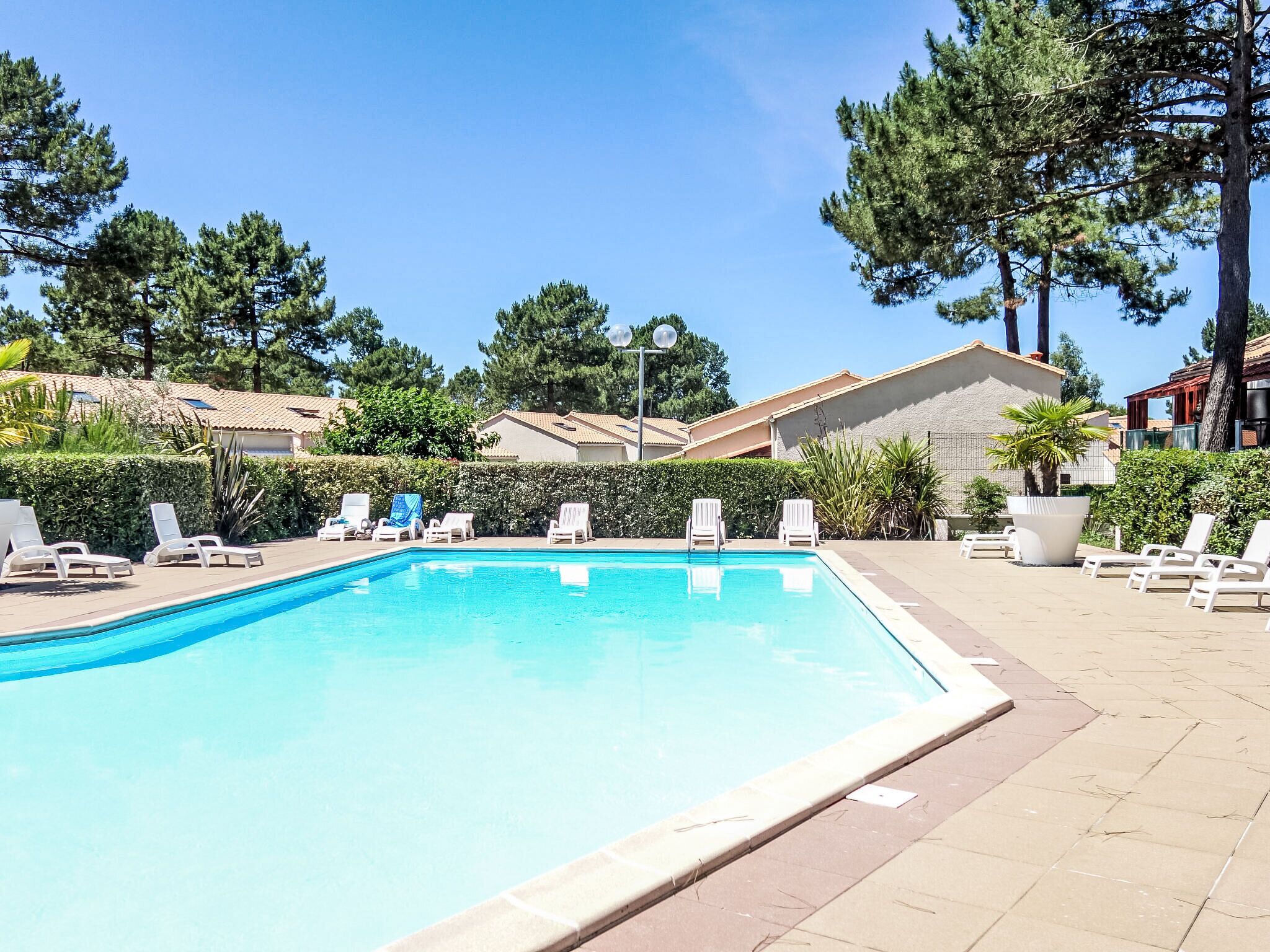 Una piscina con sillas de descanso y cielo despejado.