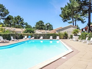 A swimming pool with lounge chairs and a clear sky. - Hameau de Talaris by Interhome (Les Mathes)