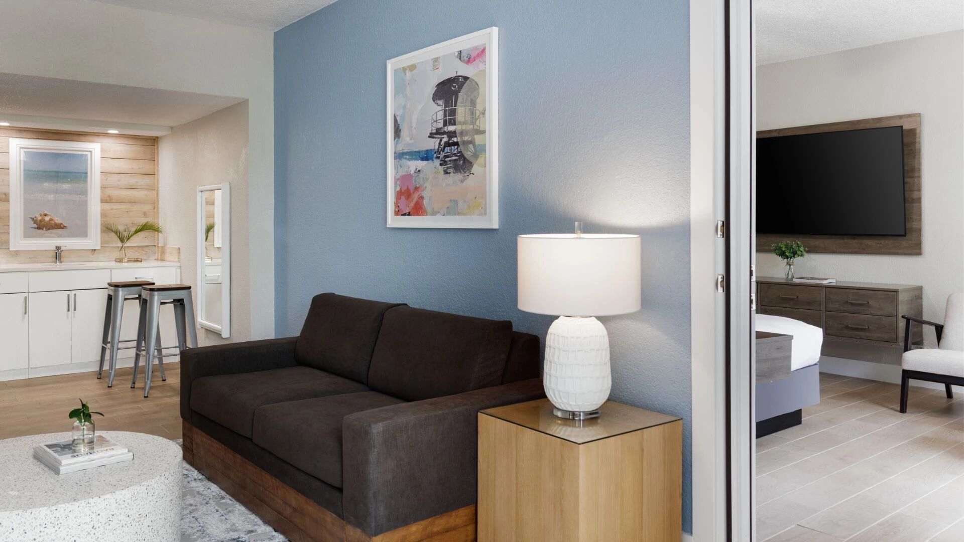A modern living room with a dark brown sofa, a white lamp, and a blue accent wall.