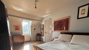 A bedroom with a bed, a radiator, a chair, and a window. - Le Nid du Matelot (Saint-Vaast-la-Hougue)