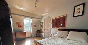 Une chambre à coucher avec un lit, un radiateur, une chaise et une fenêtre.