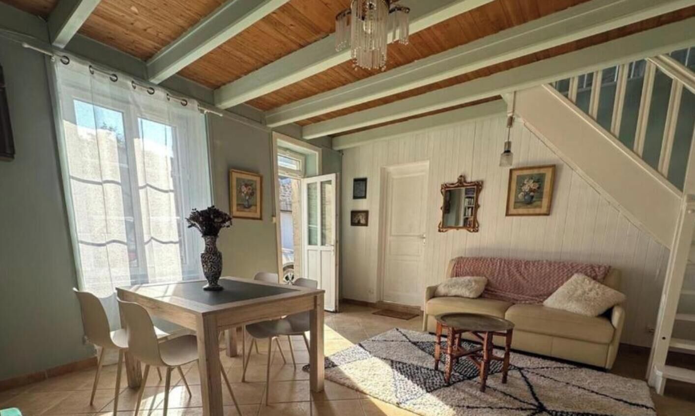 A dining area with a table and chairs, a sofa, a staircase, and a chandelier.