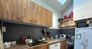 Une cuisine avec des meubles de rangement en bois, un four à micro-ondes, un réfrigérateur et une machine à café.