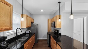 Une cuisine moderne avec des meubles en bois, des appareils en acier inoxydable et des luminaires suspendus.