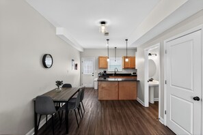 A modern kitchen with wooden cabinets, a central island, and pendant lighting. - Modern 2br Townhome in Prime Location (Clarksville)