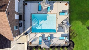 Vue aérienne d’un espace piscine sur le toit, avec une piscine rectangulaire, quatre chaises longues et deux parasols.