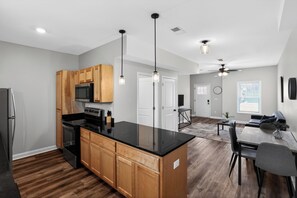 A modern kitchen with wooden cabinets, a black countertop, and pendant lighting. - Relaxing 2BR Stay with Community Perks (Clarksville)