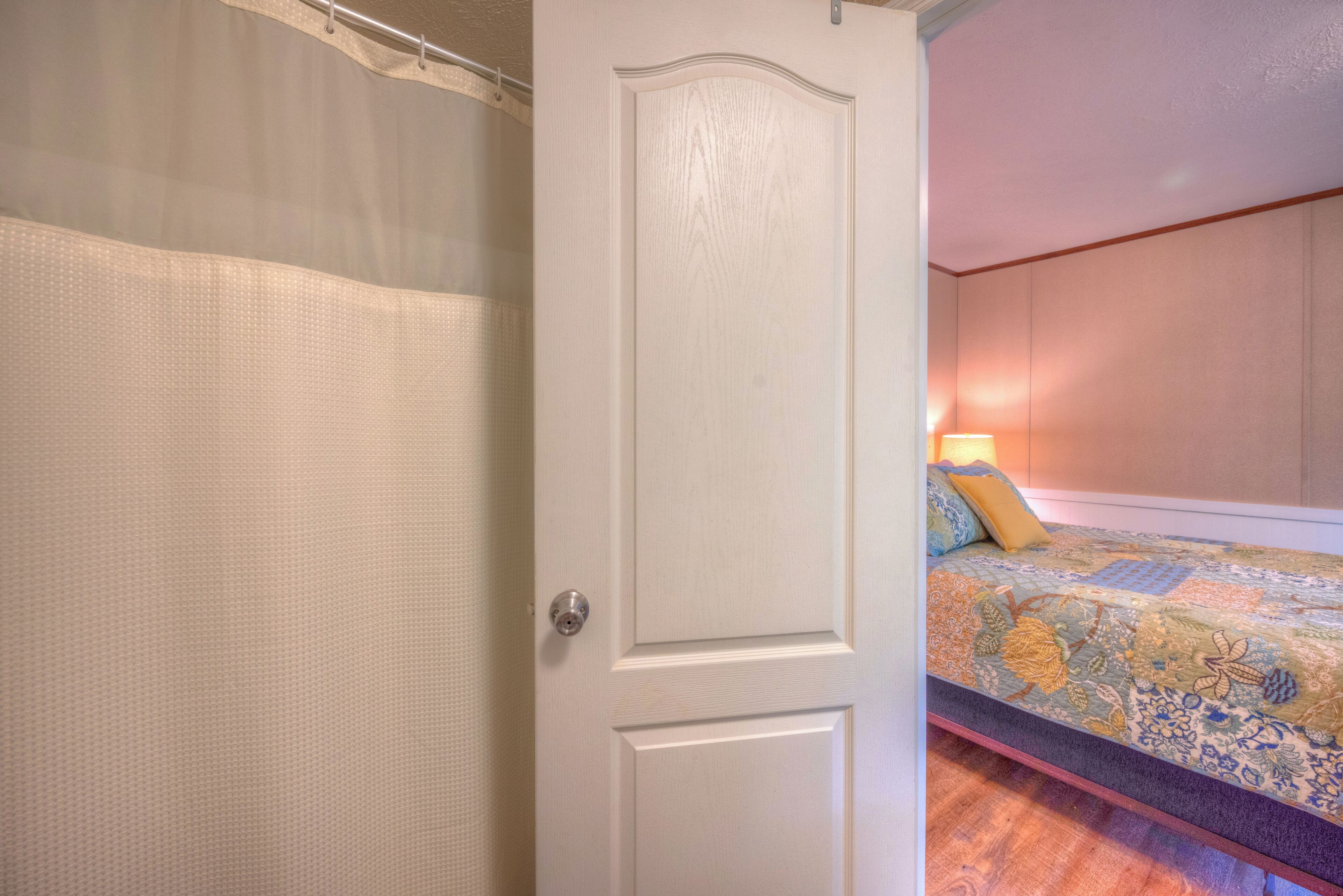 A bedroom with a bed, a door, and a curtain.