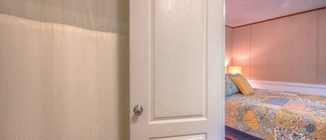 A bedroom with a bed, a door, and a curtain.