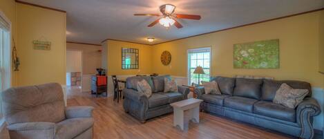A living room with a ceiling fan, a sofa, a chair, and a small table.