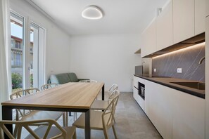 Eine moderne Küche mit einem Holzespeisetisch, weißen Stühlen und einem eingebauten Backofen.