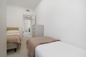 Ein Schlafzimmer mit zwei Betten, einem Kleiderschrank und einer Tür zu einem anderen Raum.