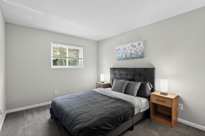 A bedroom with a bed, a nightstand, a bedside lamp, a window, and a wall-mounted painting. - Elegant Chateau Escape | Parking Included (Wilmington)