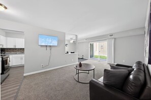 A modern living room with a flat-screen TV, a leather sofa, and a small coffee table. - Elegant Chateau Escape | Parking Included (Wilmington)