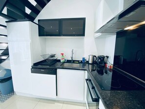 Uma cozinha compacta com lava-louças, pia, fogão e micro-ondas.