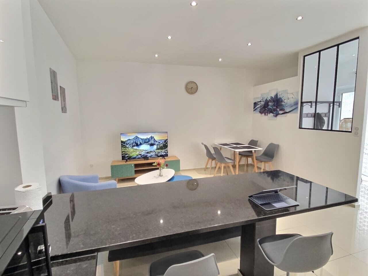 Uma sala de estar moderna com televisão de tela plana, uma mesa de jantar e uma mesa de centro.
